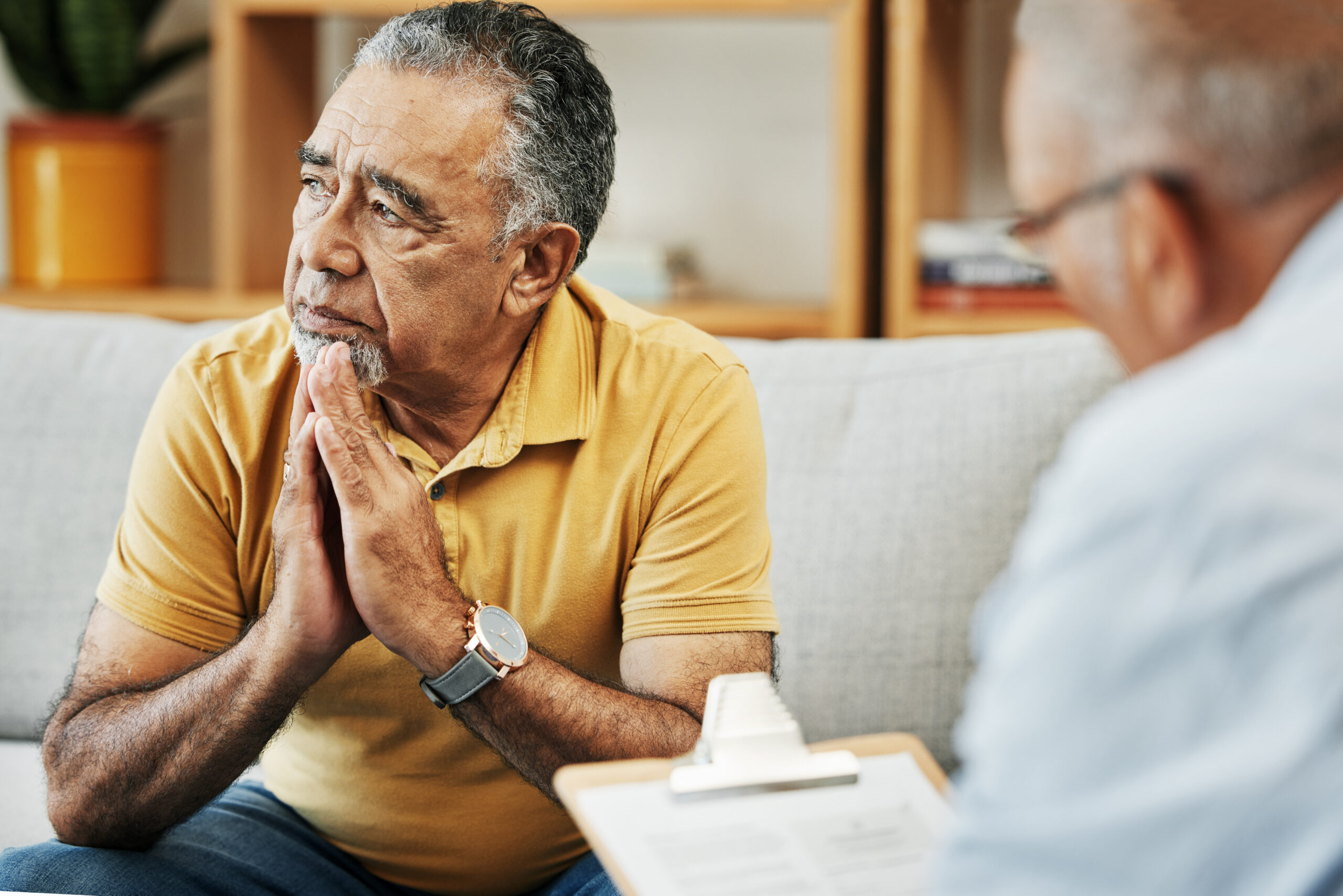 Elderly man talking to a psychologist at a mental health, psychology and therapy clinic for session. Psychological therapist with clipboard for counseling checklist with senior male patient in office Divi-Psychology-img3